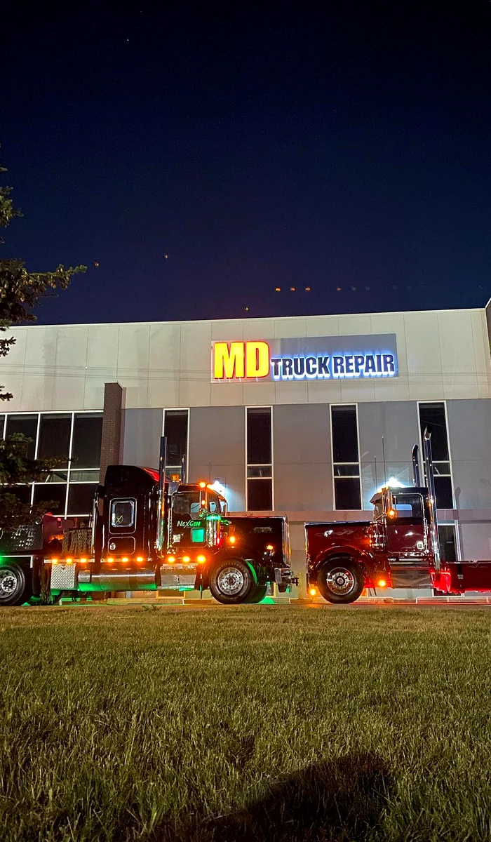 Heavy-duty trucks parked outside MD Truck Repair at night