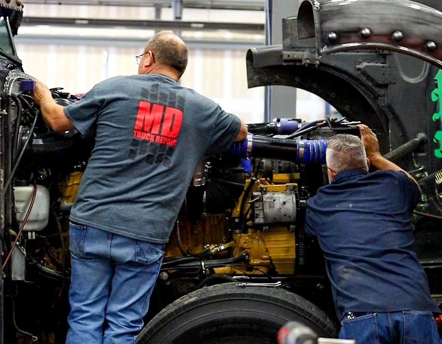 Two technicians working together on a heavy-duty truck